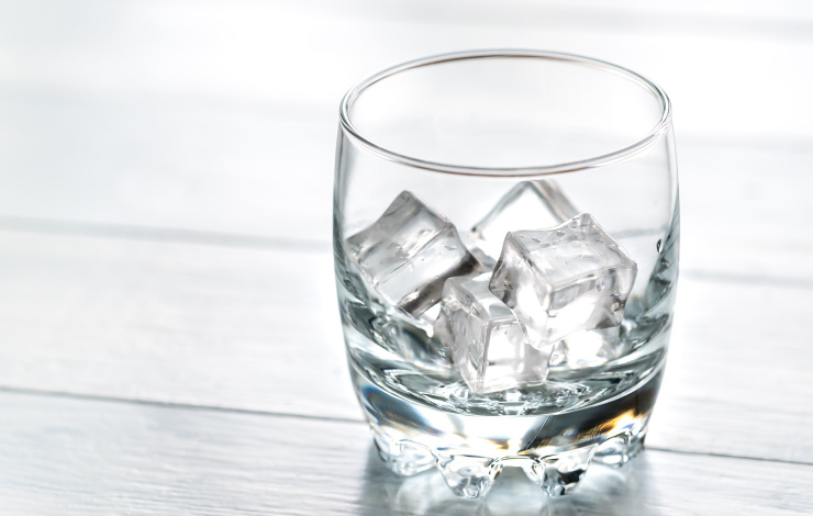 Glass with ice cubes on the wooden table
