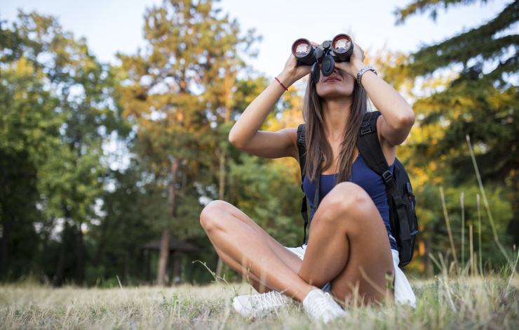 Young woman using binoculars in nature