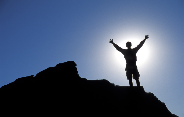 man standing on top of a mountain celebrating success