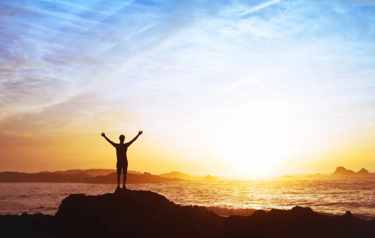 achieving a goal standing on a mountain overlooking water