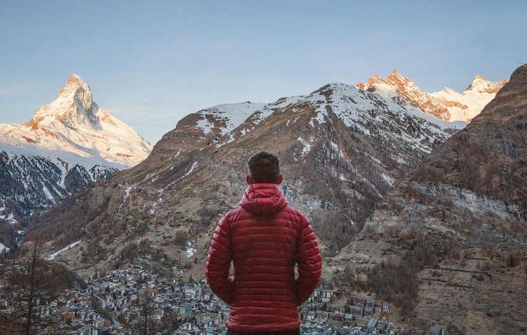 man in red jacket facing a mountain