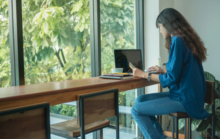 Asian young woman using laptop computer to pay shopping online, pay the bill online at coffee shop.