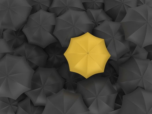 yellow umbrella in a sea of black umbrellas
