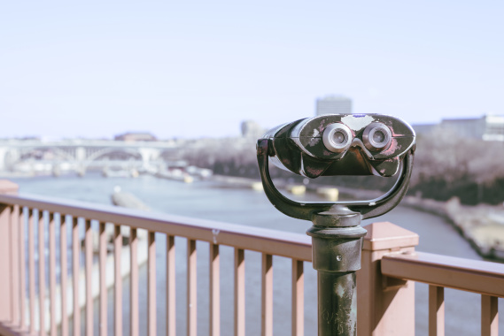retro binoculars on bridge overlooking city