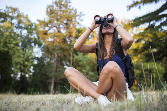 Young woman using binoculars in nature