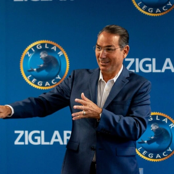 Image of Howard talking on stage with a logo background behind him