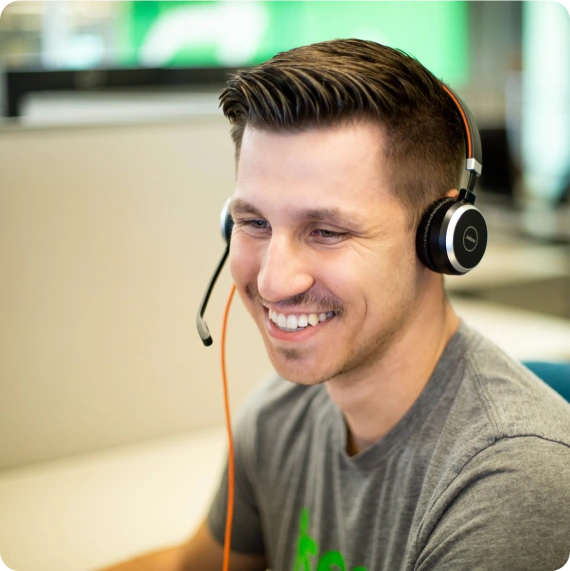 Man wearing a headset smiling taking a call from a customer.