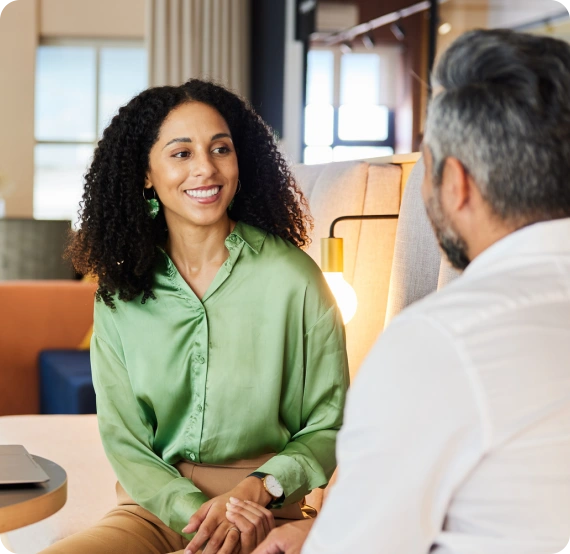 Woman smiling sitting down across from a man