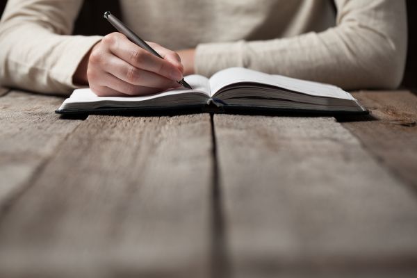 close up of a person writing in a notebook