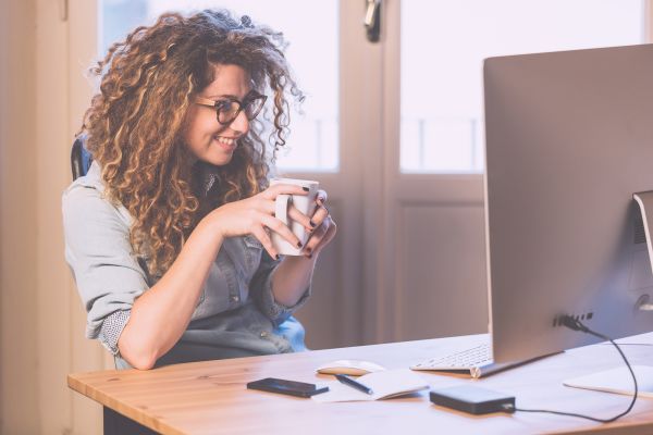Woman drinking coffee and working on computer