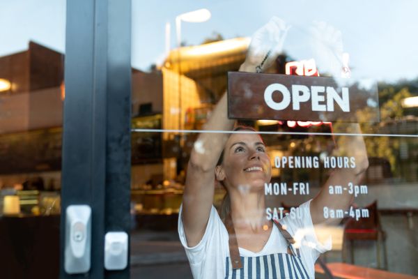 Woman hanging an open sign on business front door