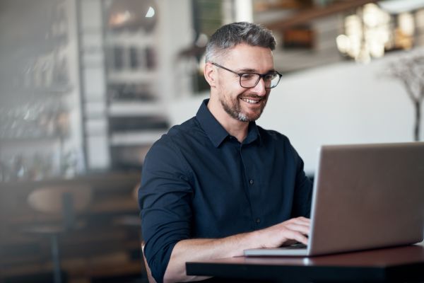 male small business owner happily working on laptop