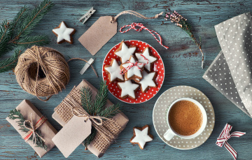 Wooden rustic background with cup of hot coffee and gift wrapping of Christmas cookies. Seasonal background shot from above. Flat lay, top view, filtered image. Tag mockup, copy space on the tags.