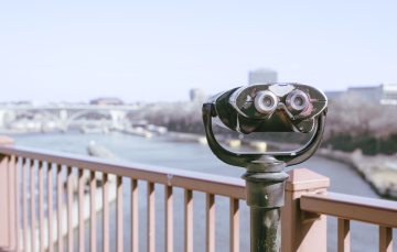 retro binoculars on bridge overlooking city