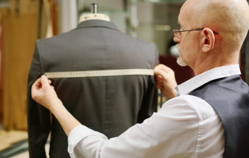 A tailor measuring the back of a suit jacket