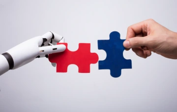 Robot and human hands holding puzzle pieces