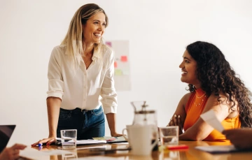 Two women smiling at each other in a meeting