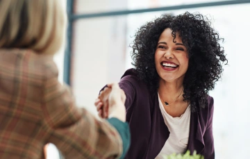Woman smiling and shaking the hand of another person