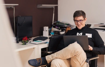 Man smiling sitting down looking at a laptop screen