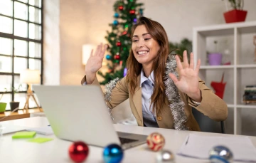 Woman smiling at a laptop with her hands up