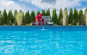 A man in a red uniform working on pool maintenance