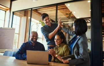 A team of professionals using a laptop and writing in a notebook, representing planning and preparation with marketing automation tools for the fall season
