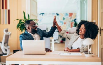 Illustration of two people high fiving in celebration, symbolizing teamwork and successful lead generation.