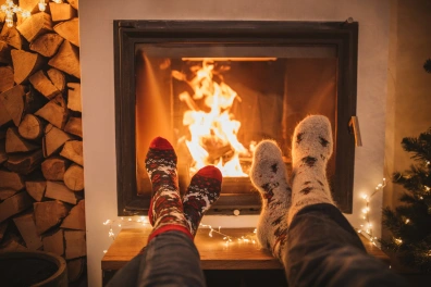 Two people with their legs crossed next to a fire place