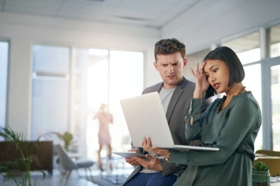 A man and woman looking perplexed while looking at a laptop screen