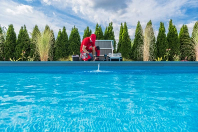 A man in a red uniform working on pool maintenance