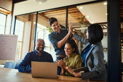 A team of professionals using a laptop and writing in a notebook, representing planning and preparation with marketing automation tools for the fall season