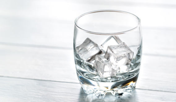 Glass with ice cubes on the wooden table