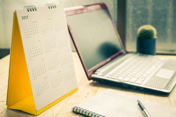 Calendar and computer sitting on desk