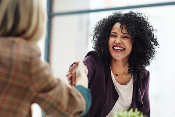 Woman smiling and shaking the hand of another person