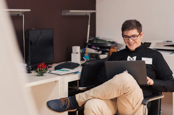 Man smiling sitting down looking at a laptop screen