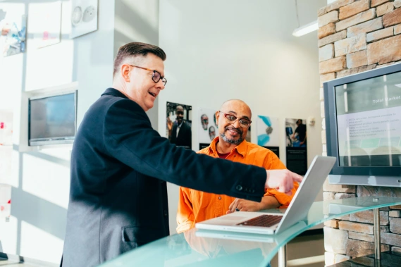 Two men looking at a laptop screen smiling