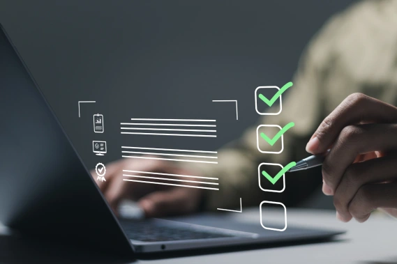Hand writing a holographic checklist with laptop in the background