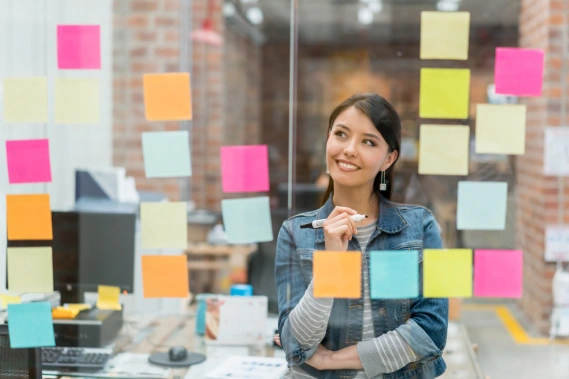 Woman standing in front of a board of different color sticky notes