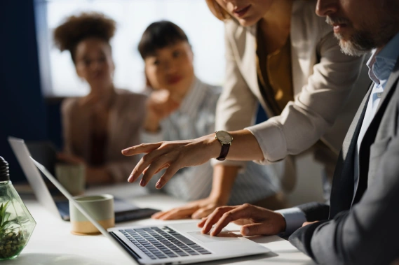 A business team working together in front of a laptop.