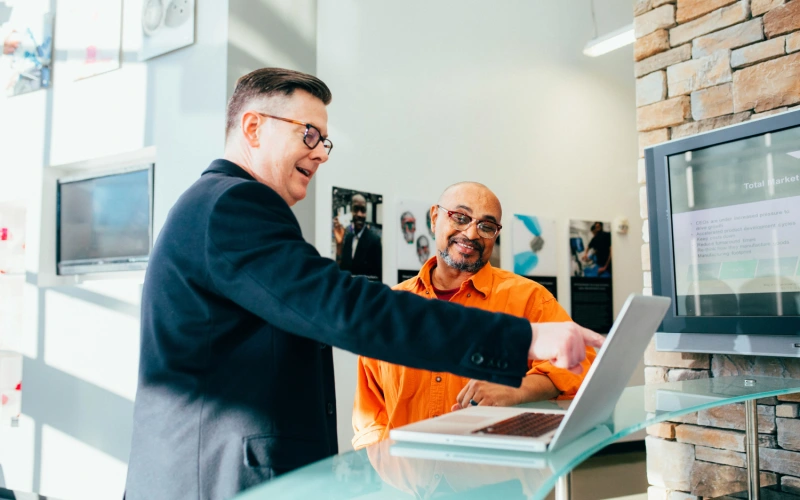Two men looking at a laptop screen smiling