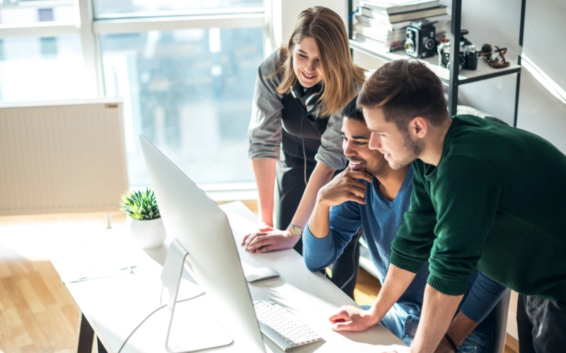Three people looking and pointing at a computer screen